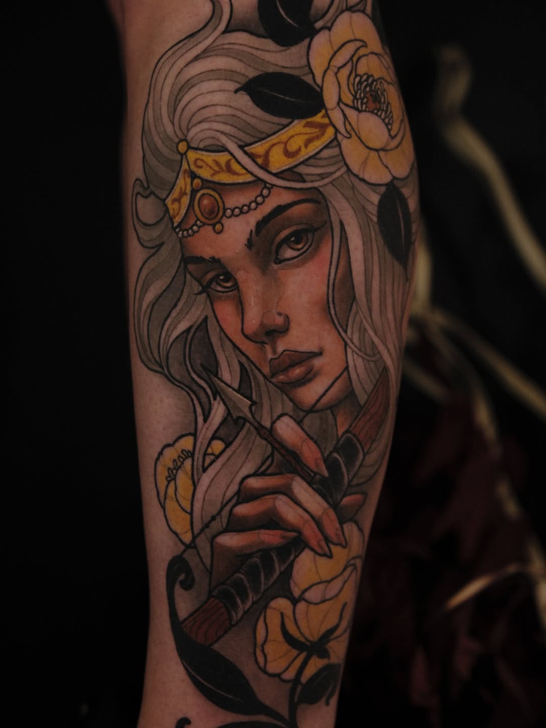 Female face portrait with flowing hair, gold headpiece, and yellow flowers adorning the shoulder and arm area, rendered in brown and black ink.