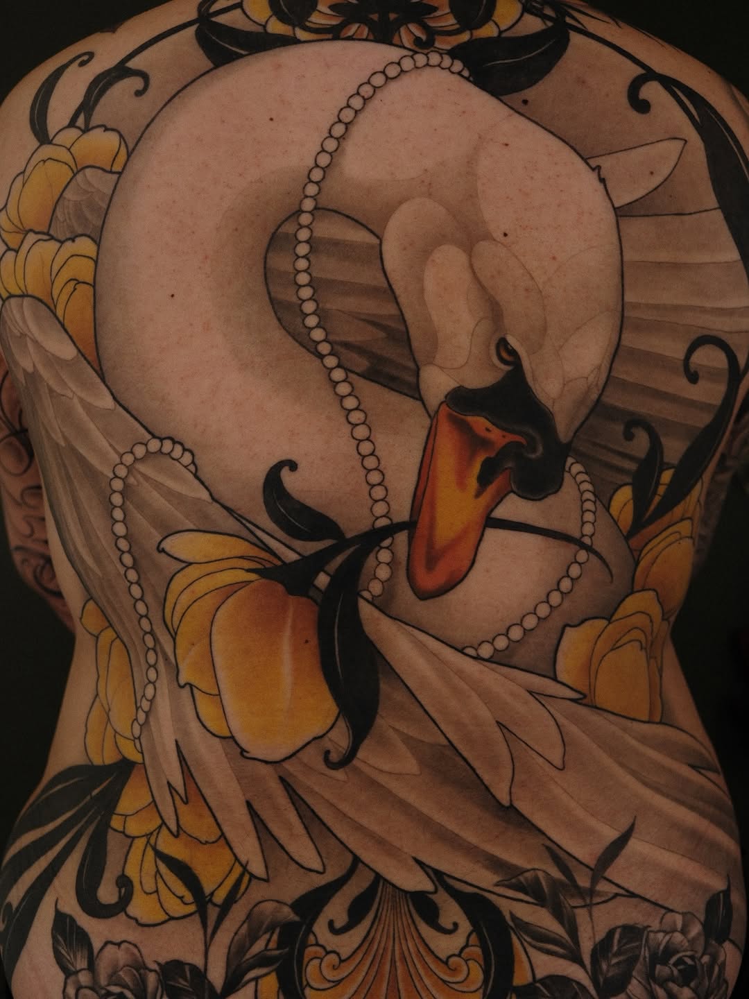 Swan with pearl strands and yellow flowers in full color covers the upper back, featuring orange and black details with decorative flourishes.