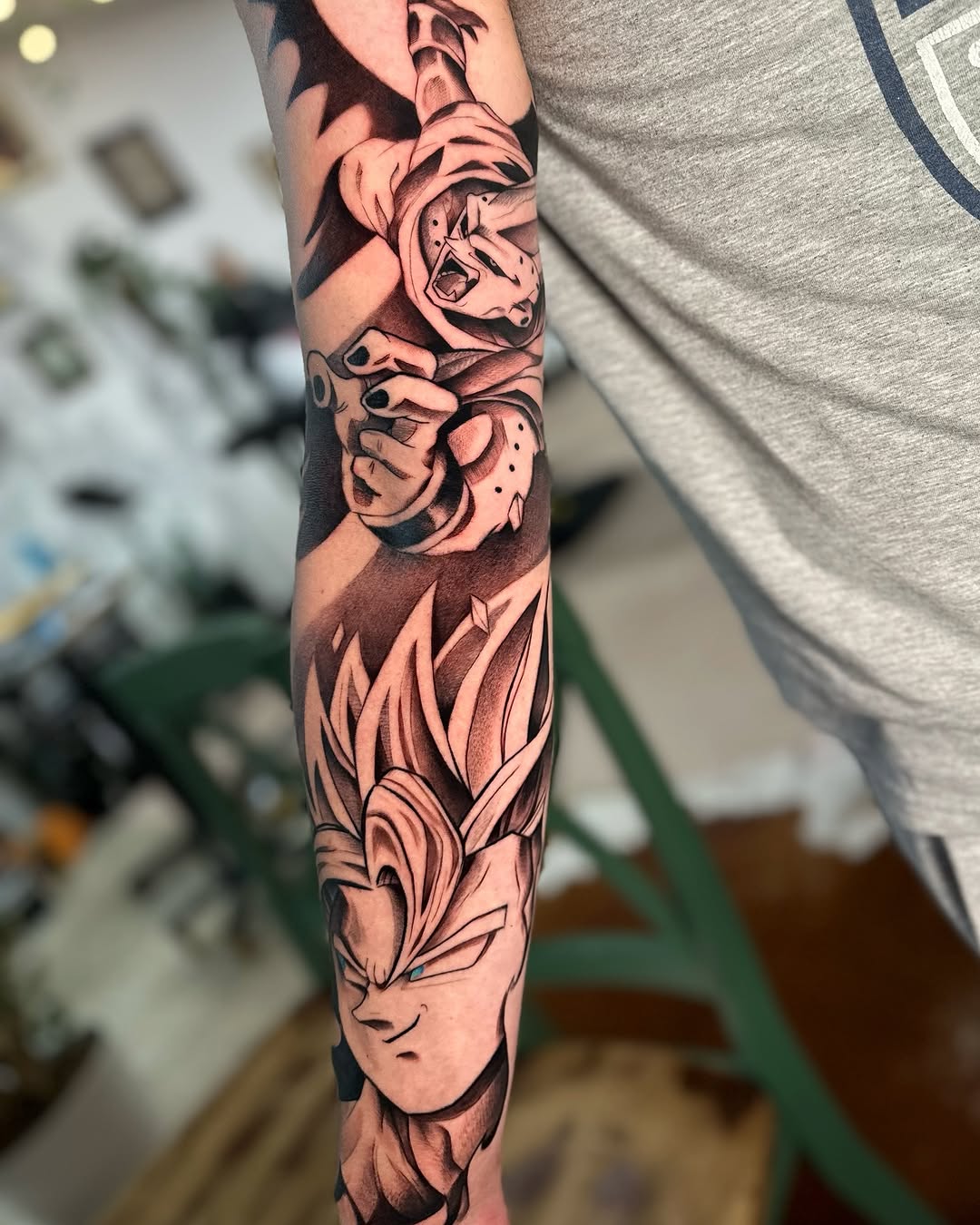 Full-sleeve arm tattoo featuring stacked character faces with expressive emotions, flame designs, and floral elements in black and brown ink.