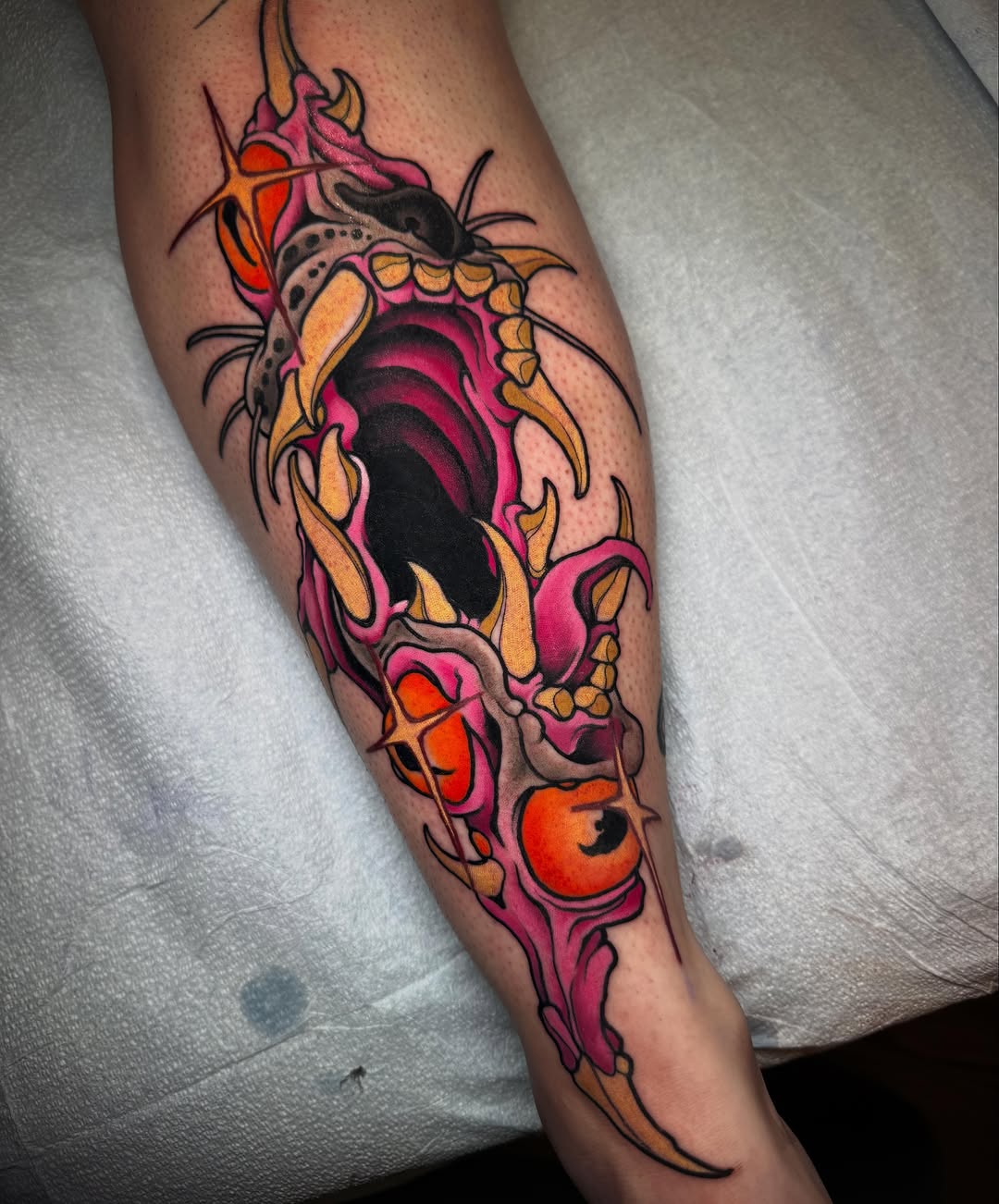Colorful beetle tattoo on forearm featuring pink, orange, yellow, and black wings with detailed antennae and segmented body design.