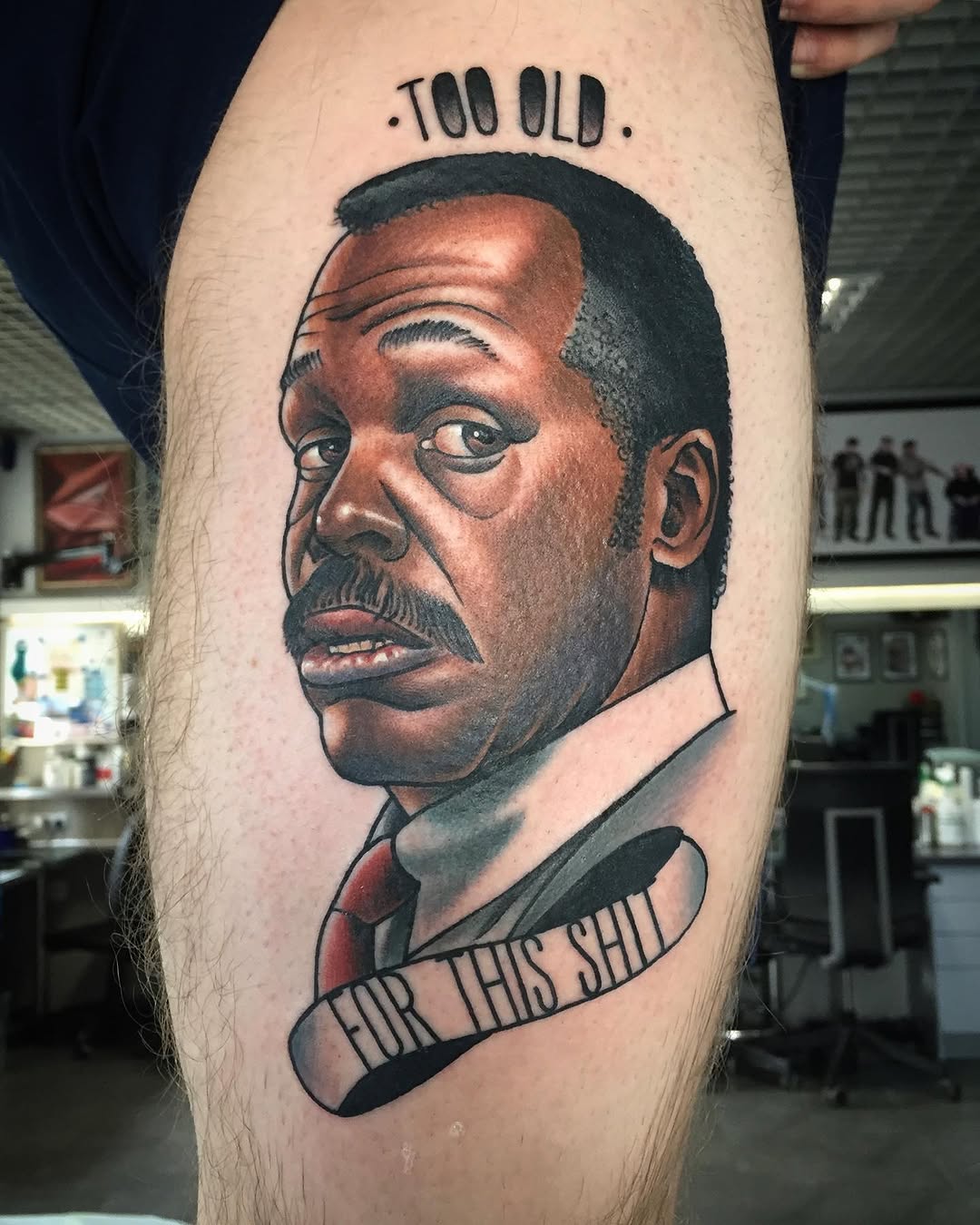 Portrait tattoo on upper leg featuring a man's face with facial hair, text reading "TOO OLD" above and "FOR THIS SHIT" below, in brown and black ink.