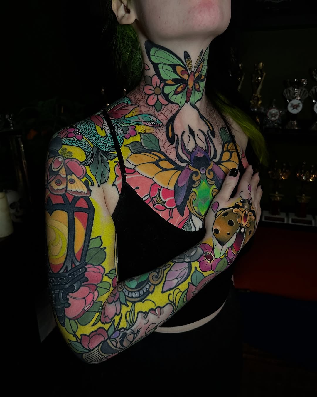 Colorful full-arm tattoo sleeve featuring insects, flowers, and botanical elements in pink, yellow, green, and orange on neck and upper body.