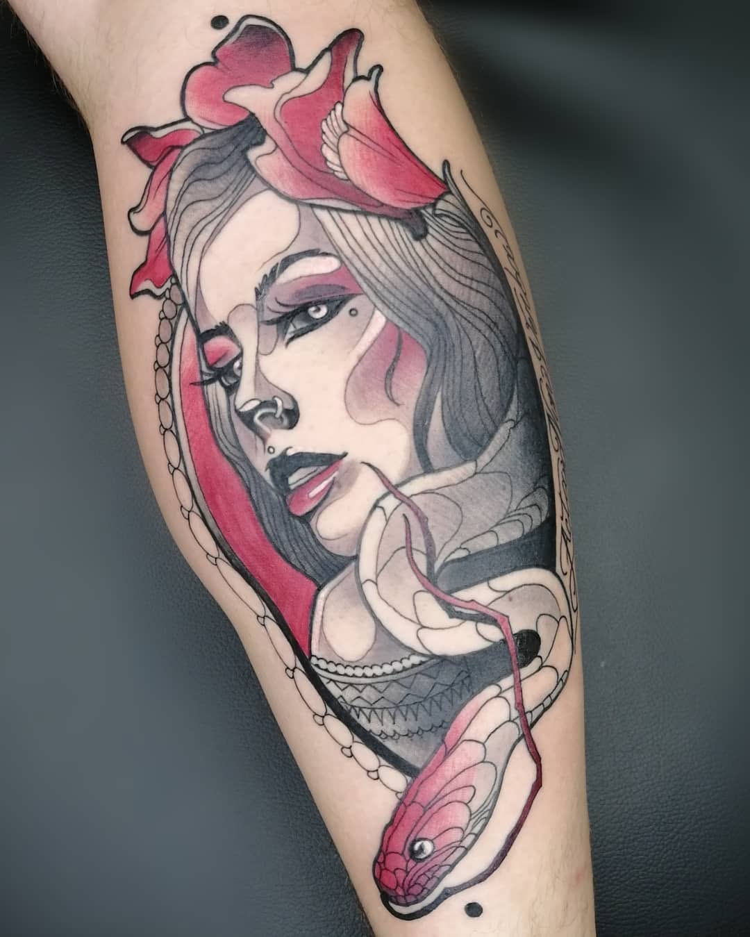 Portrait tattoo of a woman's face with pink and gray coloring, ornate clothing details, and decorative elements on the upper arm.