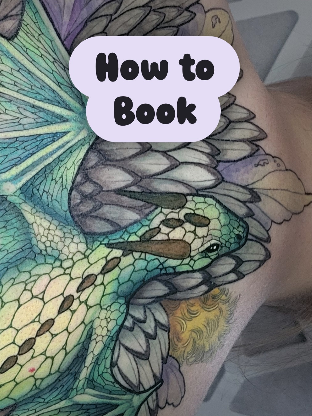 Colorful dragon head tattoo on arm featuring turquoise, purple, and yellow scales with detailed feathering and shading.