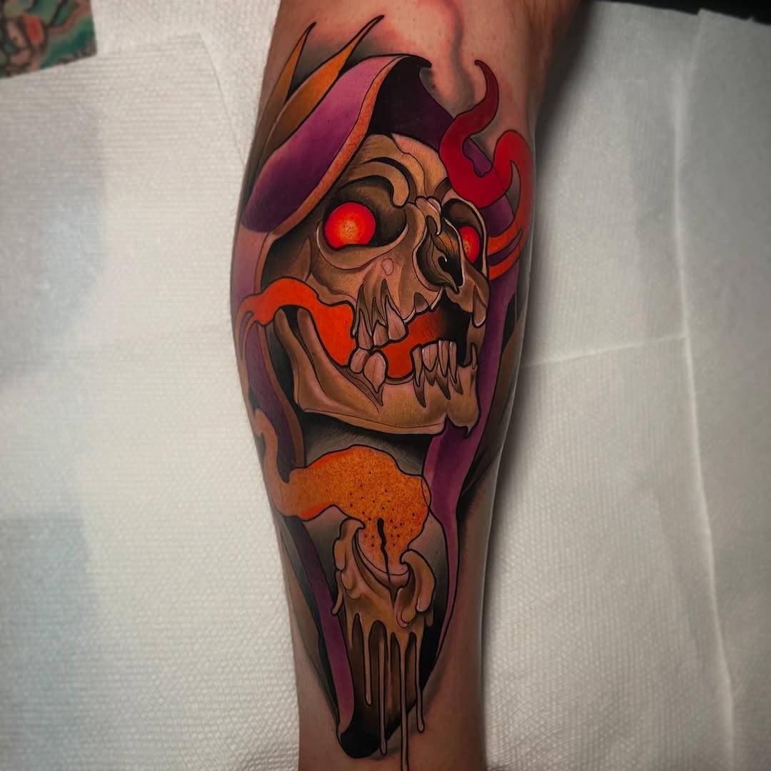 Skull tattoo on calf with glowing red eyes, purple and orange gradient background, featuring horns and dripping elements in warm earth tones.