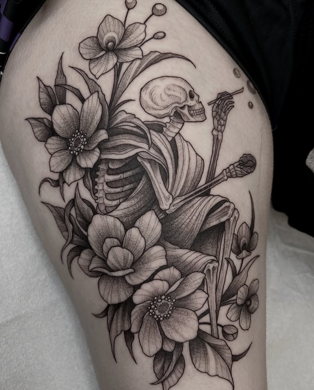 Skeleton holding flowering plants and botanical stems on upper thigh, rendered in black ink with detailed linework and shading.