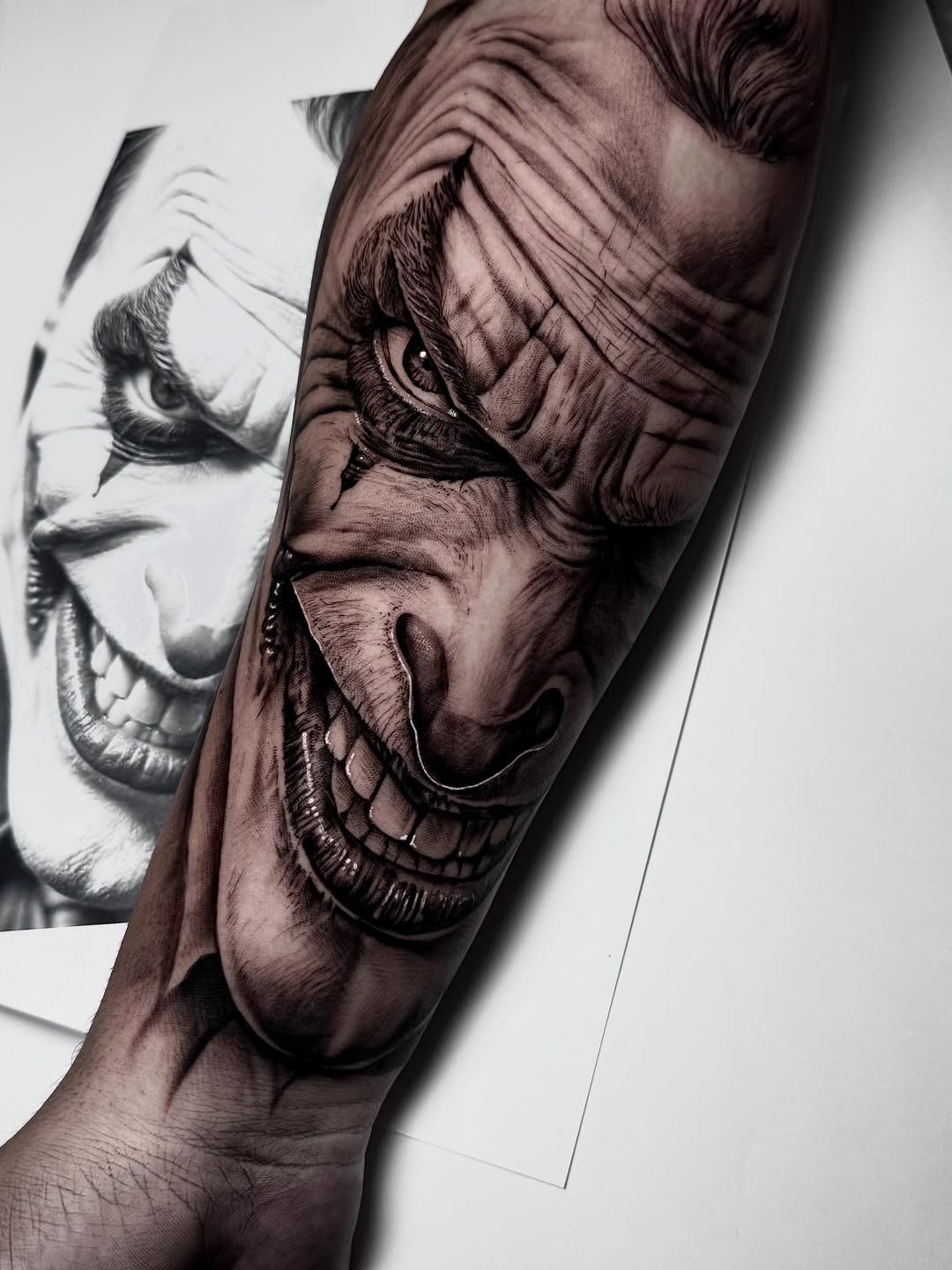 Detailed skull and skeletal face tattoo on the forearm in grayscale tones, showing intricate shading and anatomical line work.