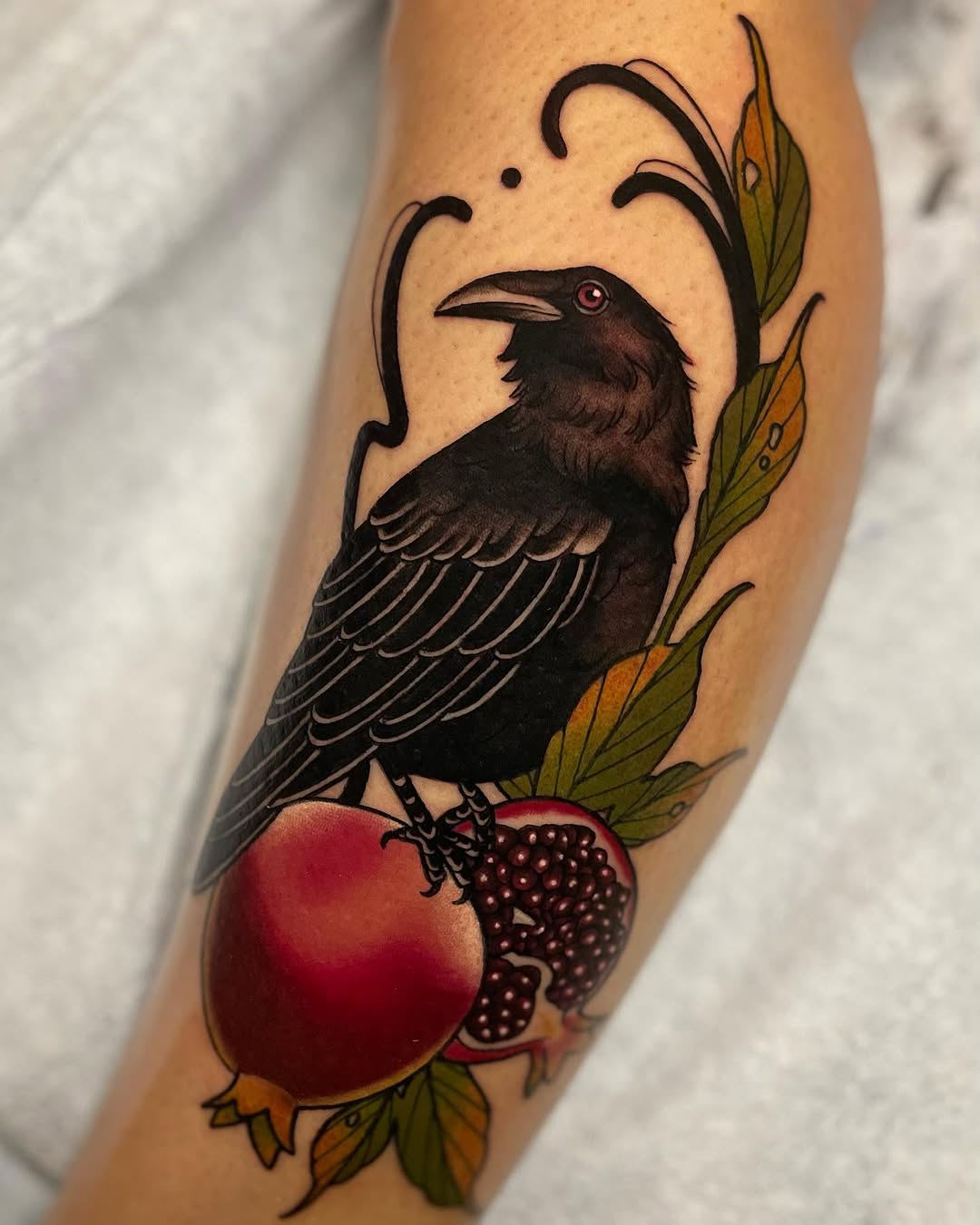 Black crow perched on red and blackberry fruits with green leaves on the upper arm, featuring detailed wing feathers and a red eye.