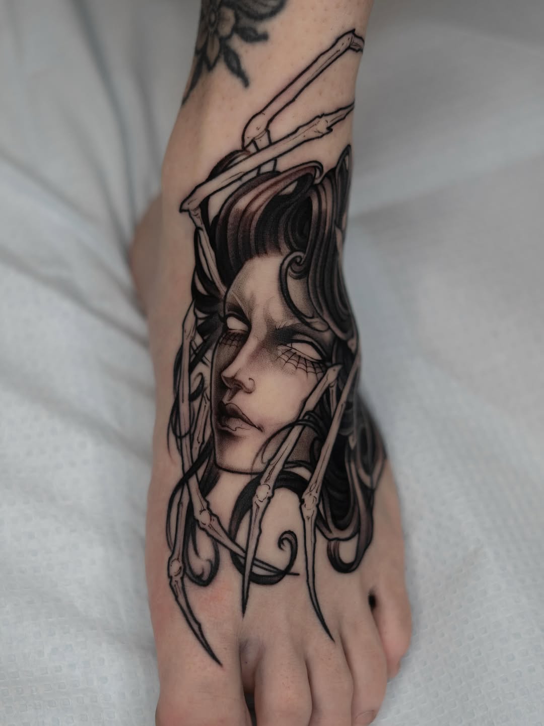 Woman's hand featuring a detailed portrait of a face with long hair and decorative line work elements in black ink.