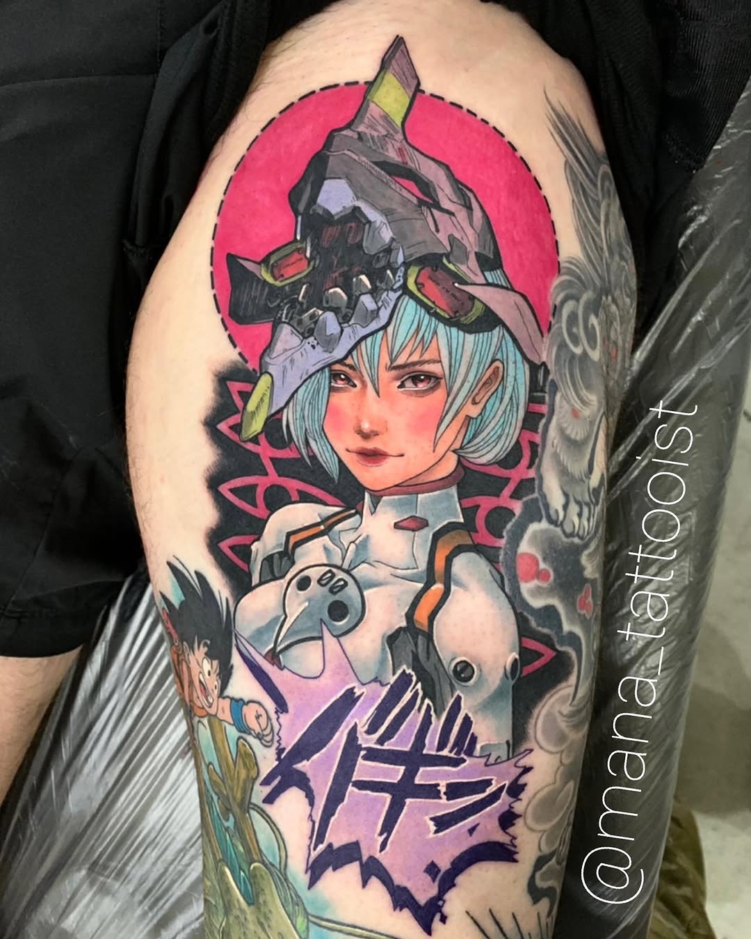 Colorful shoulder tattoo featuring an anime-style character with light blue hair, wearing a red circular halo and ornate headpiece, holding a game controller.