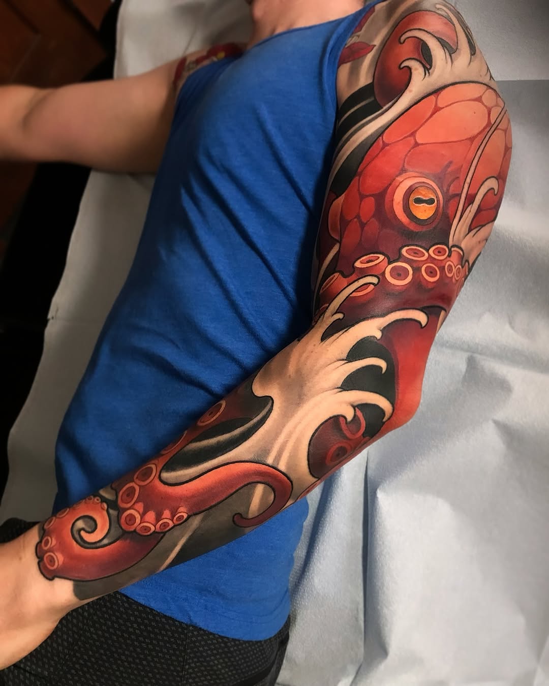 Red and black octopus with decorative tentacles and circular suction cups wrapping around the entire forearm and upper arm.
