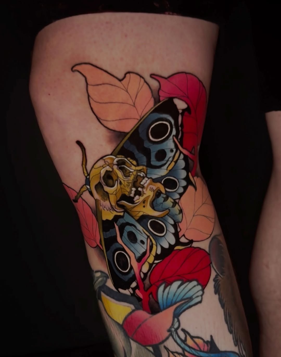 Colorful tattoo on leg featuring a butterfly with blue and black wings, golden tiger head, and red and orange petals surrounding the composition.