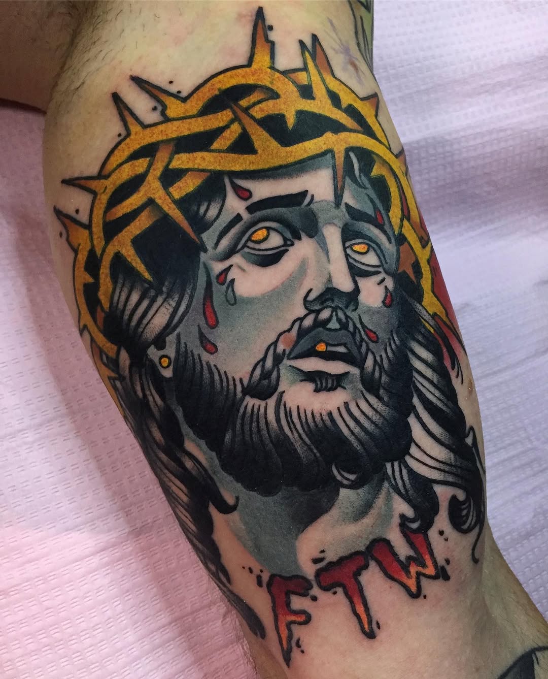 Bearded male head with golden spiked crown and orange eyes on upper arm, featuring black, gray, red, and gold coloring with dripping elements below.