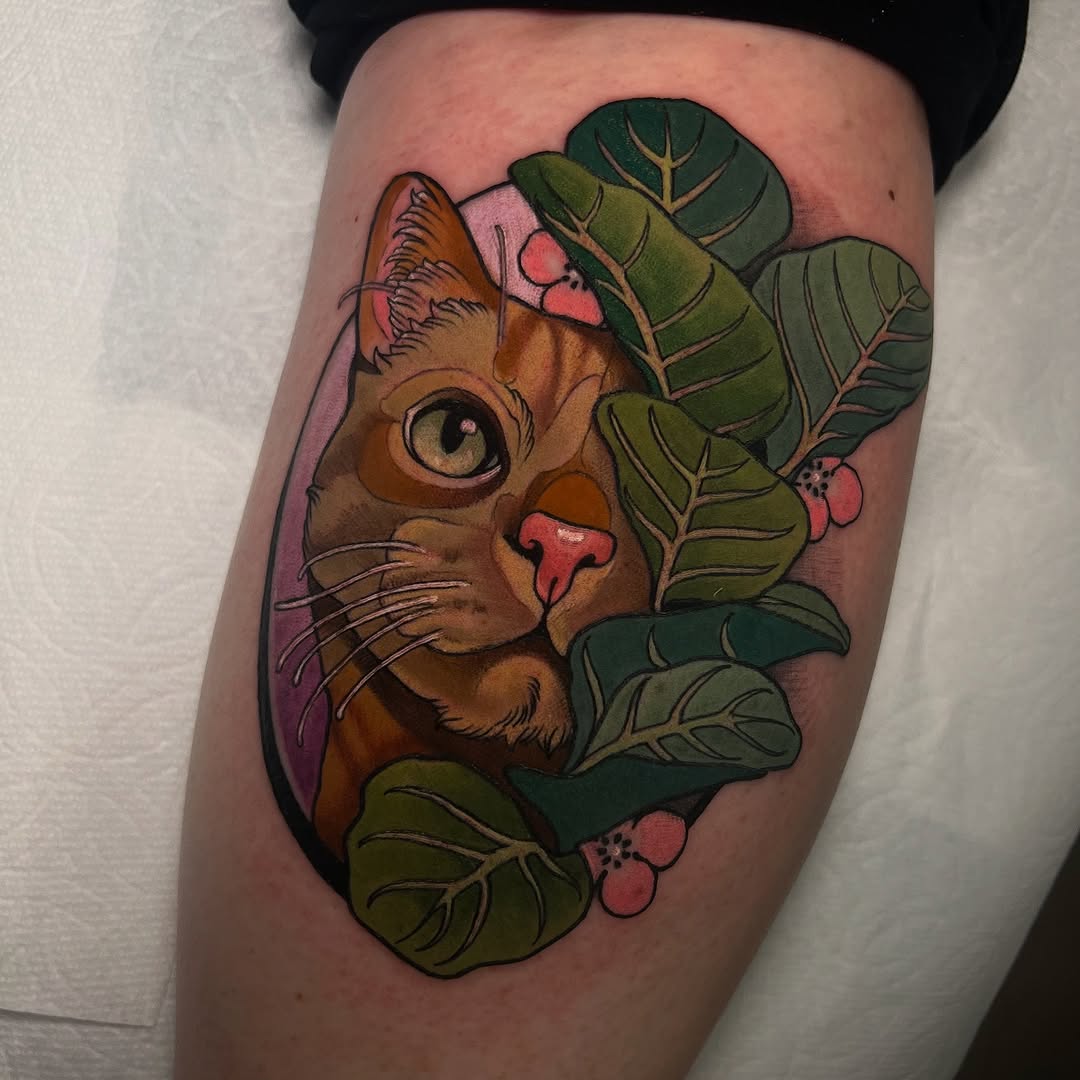 A brown cat head with large green eyes and pink nose surrounded by green leaves and pink berries on the thigh.