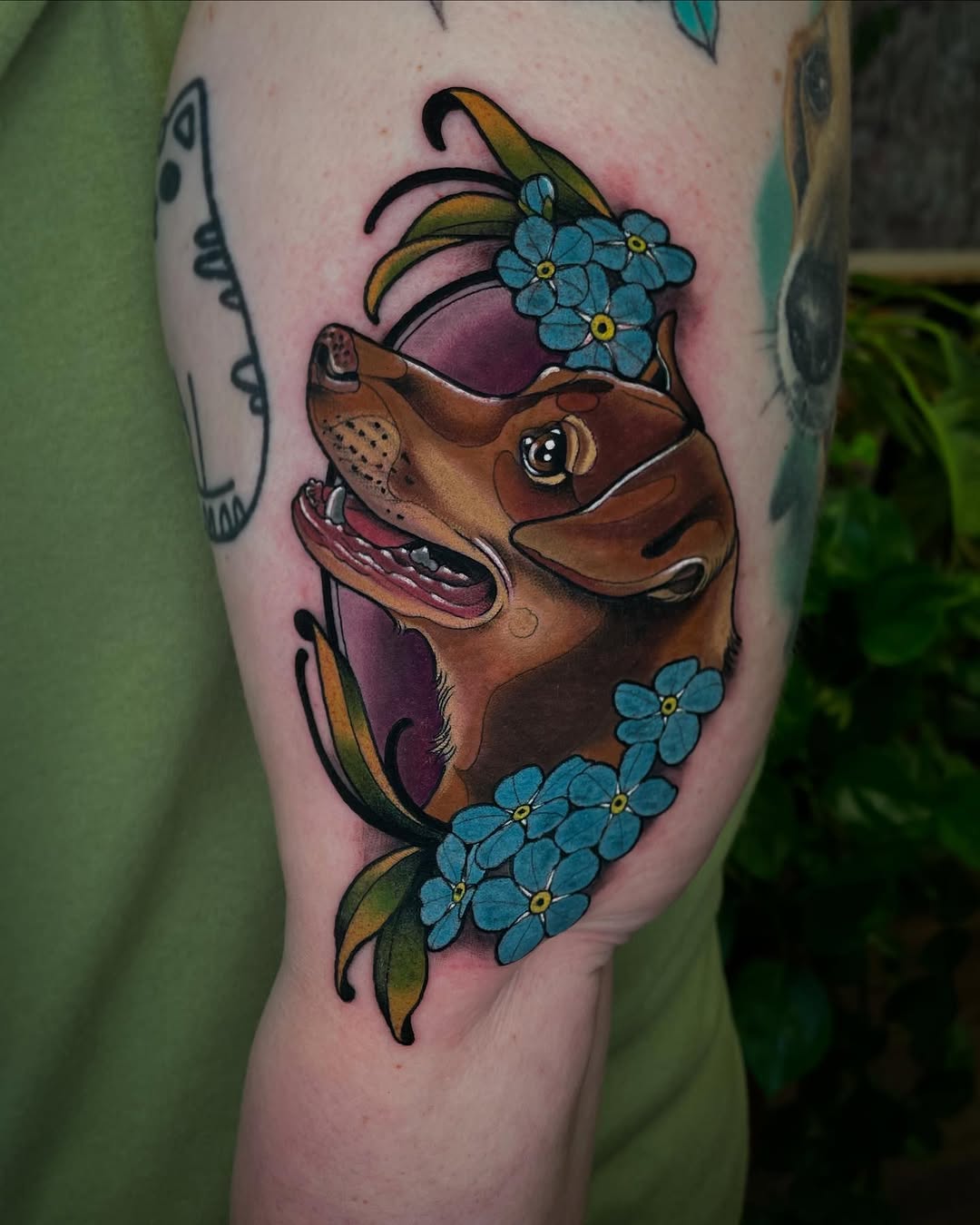 Brown horse head with expressive eyes and open mouth, surrounded by blue forget-me-not flowers and green leaves, tattooed on thigh with pink shading.