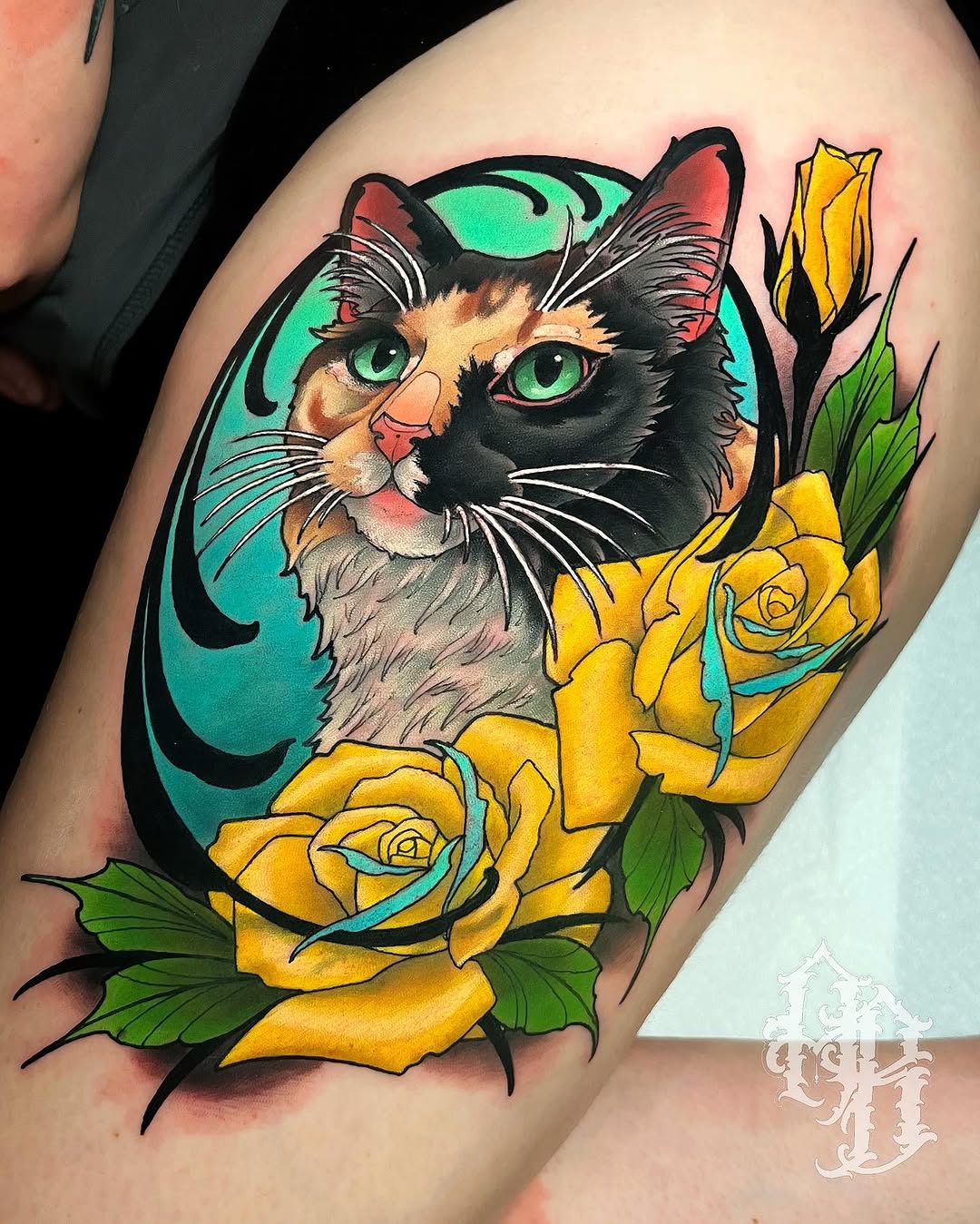 Colorful cat tattoo with striking green eyes surrounded by yellow roses and green foliage on upper arm, featuring turquoise background.