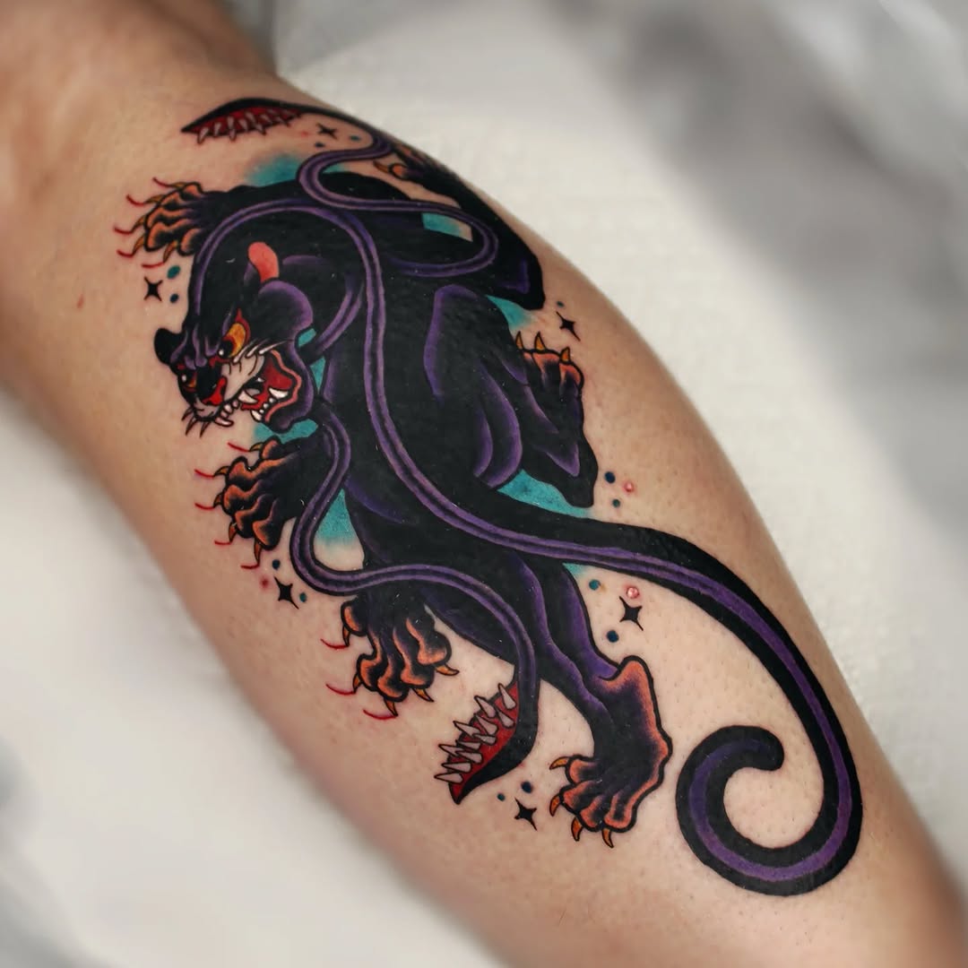 Colorful tattoo on a calf featuring two demon faces with red and orange features connected by purple serpentine lines, adorned with small stars and turquoise accents.