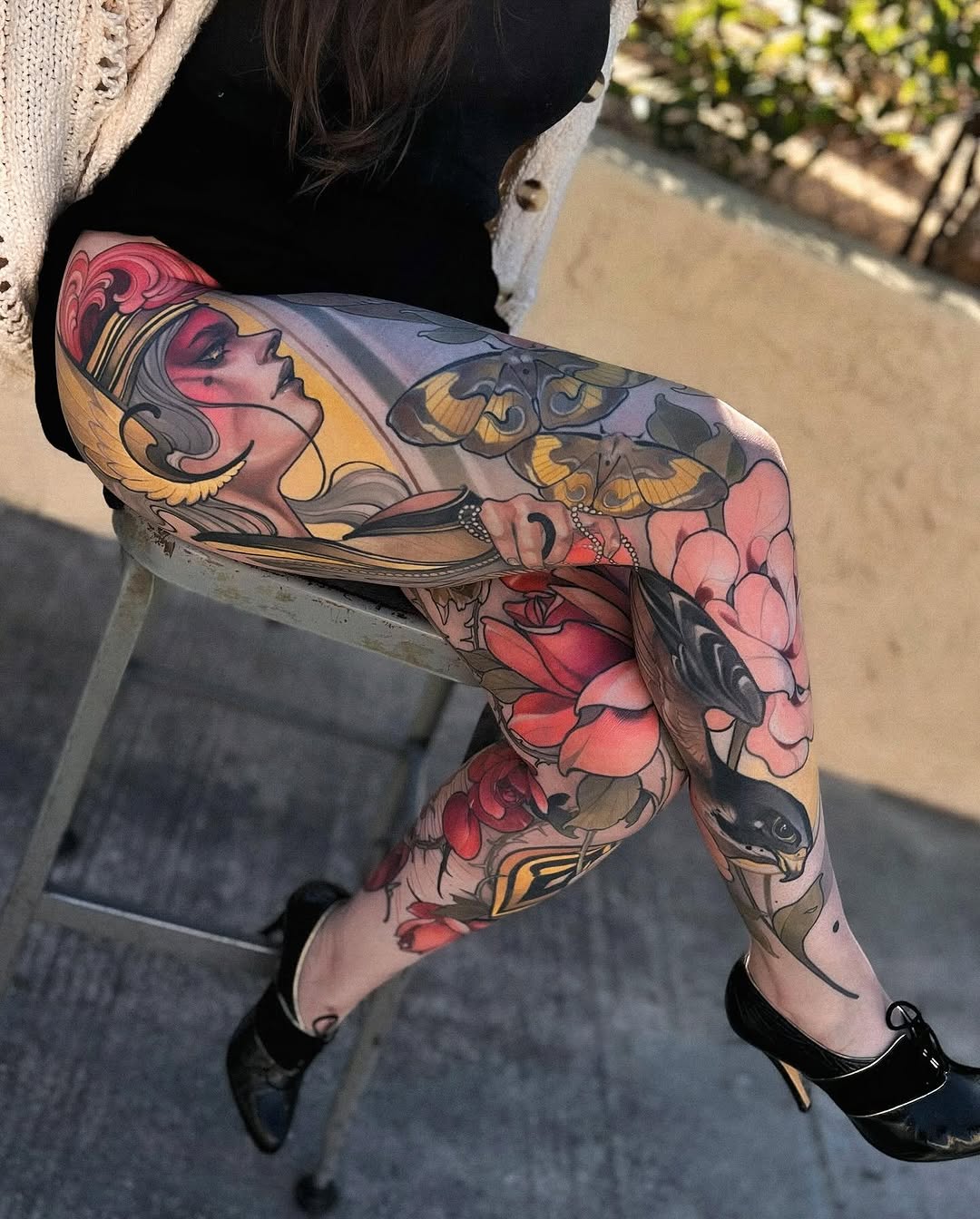 Full-leg sleeve tattoo featuring a woman's profile, butterflies, flowers, and ornamental designs in red, gold, black, and pink tones on the thigh and calf.